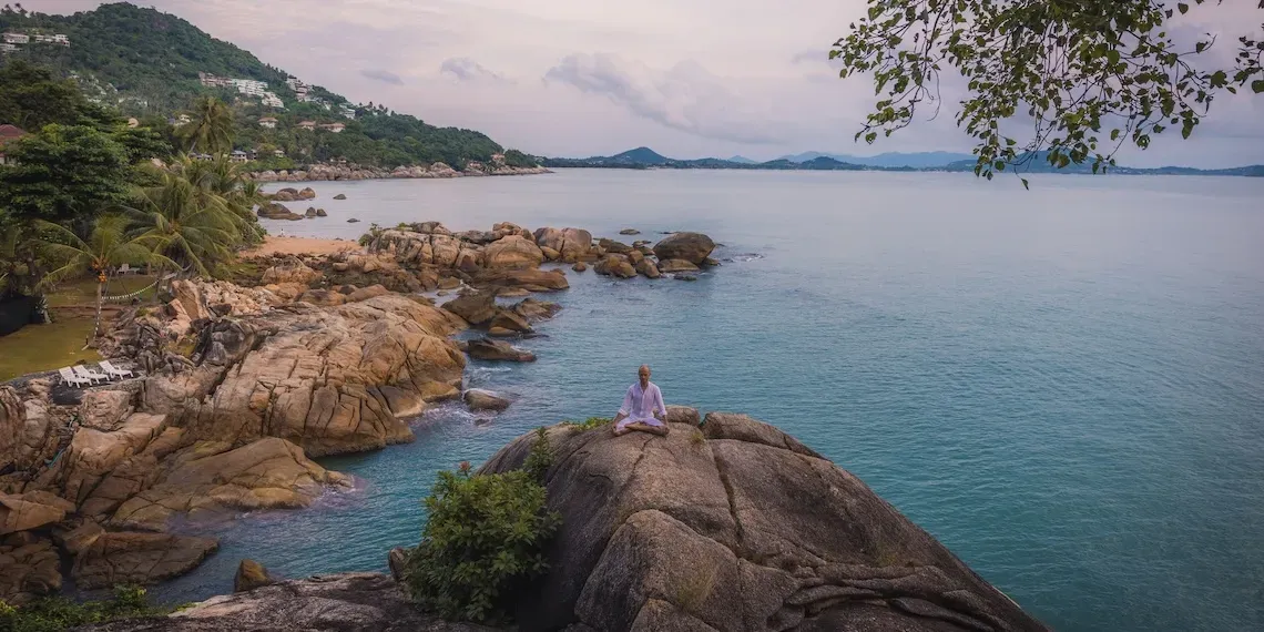 man in lotus yoga houding op een rots bij de zee