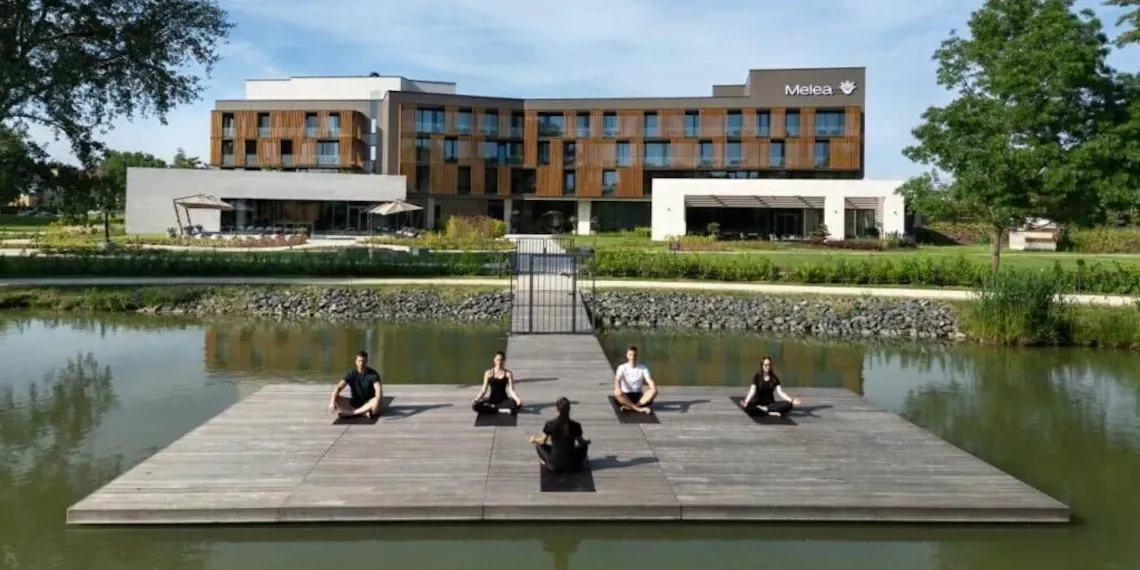 yoga bij het meer met hotel op de achtergrond