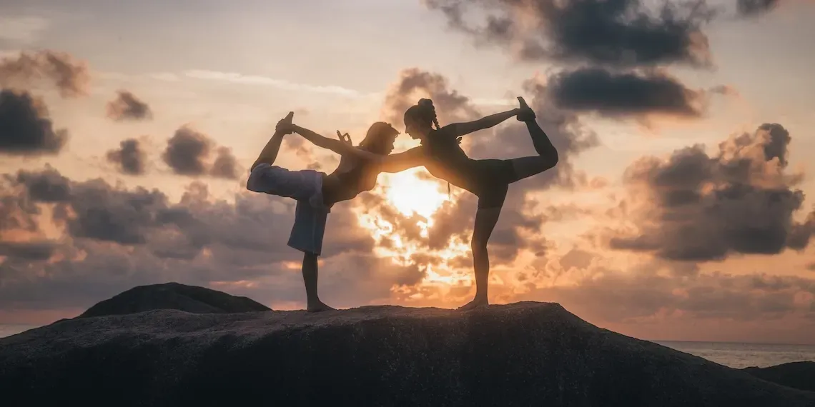 twee mensen doen yoga op rotsen