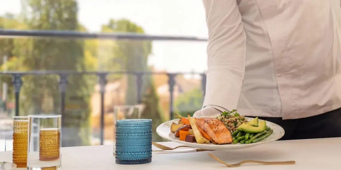 ober serveert het eten met zalm, groenten en avocado