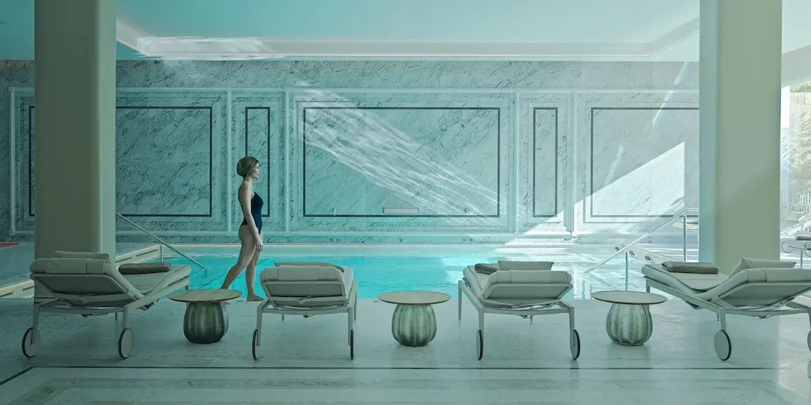 vrouw in een witte spa ruimte die loopt bij een zwembad en ligbedden
